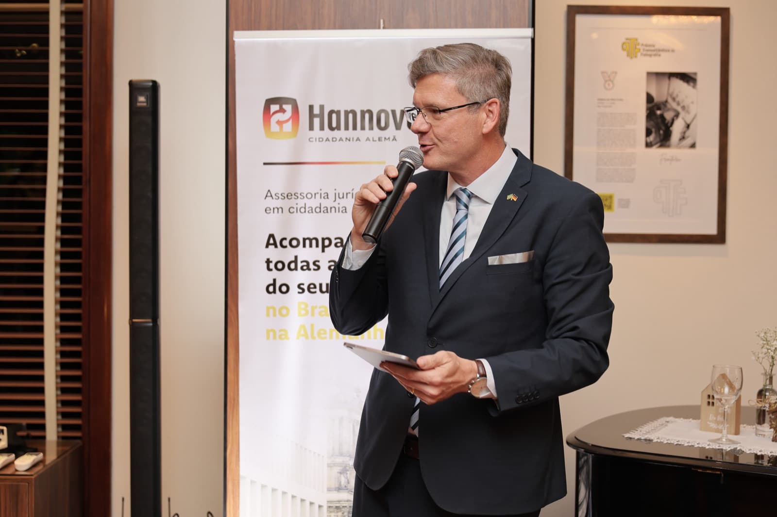 Fabio Werlang discursa no lançamento do Danke!, em frente ao painel da Hannover Cidadania Alemã
